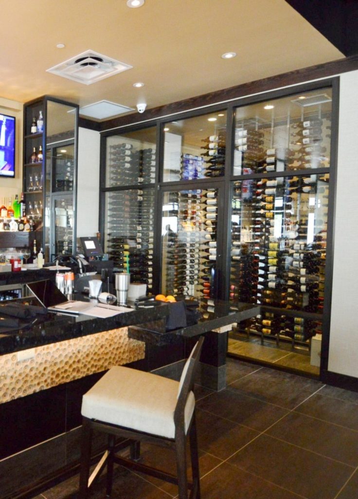 This contemporary commercial custom wine cellar in Atlanta, Georgia, displays the wines in metal wine racks.